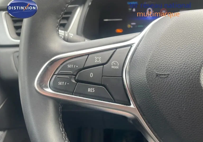 Gros plan sur les commandes de régulateur de vitesse au volant d’un Renault Captur noir étoile métal avec toit gris.