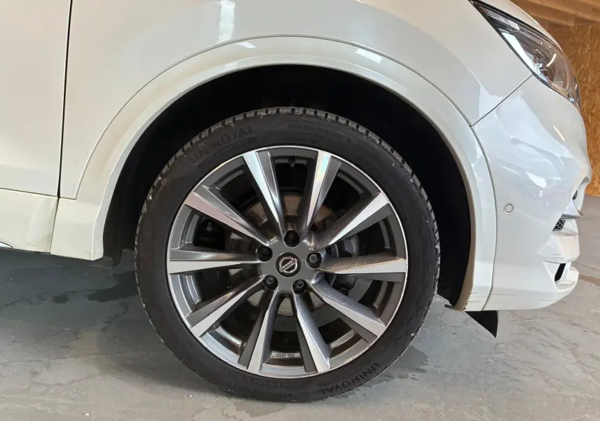 Gros plan sur la roue avant droite du Nissan Qashqai blanc 2021, mettant en valeur la jante alliage et le pneu UniRoyal.