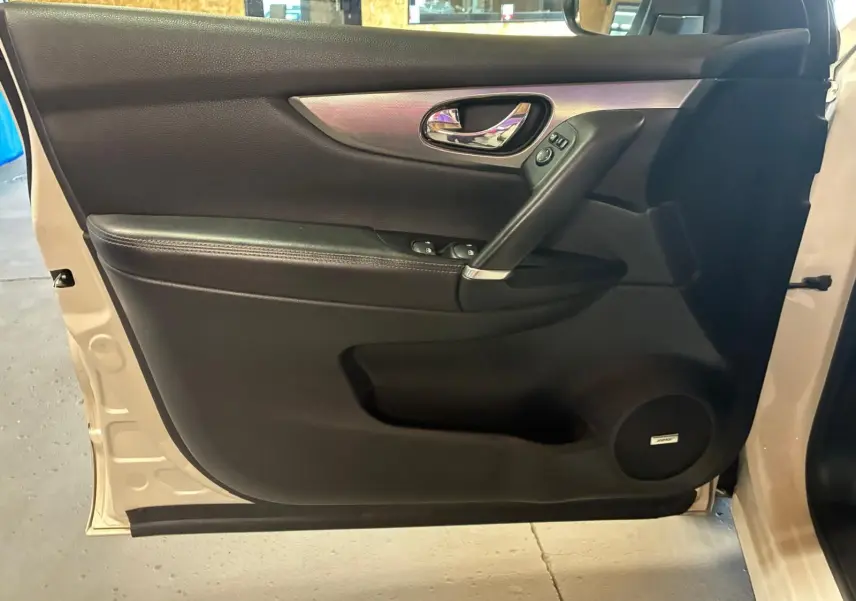 Vue intérieure de la porte avant gauche du Nissan Qashqai blanc, avec garniture noire et haut-parleur Bose intégré.