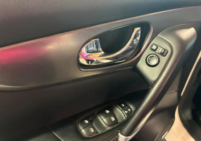 Gros plan sur la poignée intérieure et les commandes des vitres côté conducteur du Nissan Qashqai blanc, finition Tekna+ 2021.
