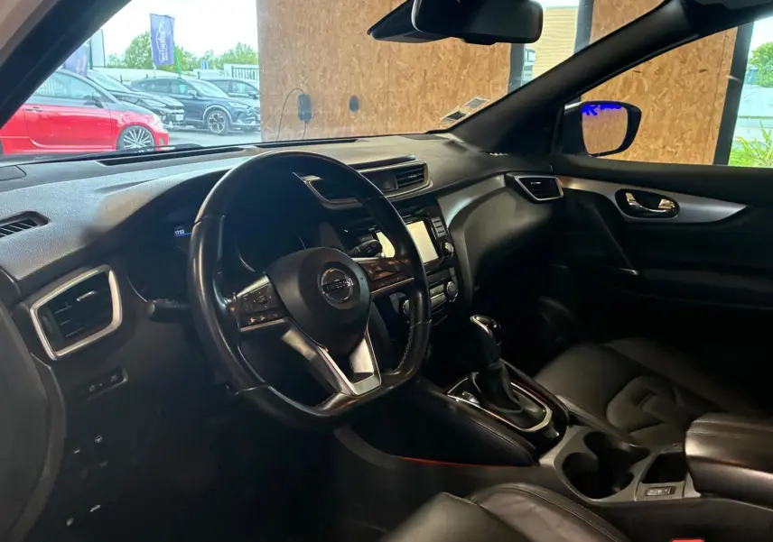 Vue intérieure côté conducteur du Nissan Qashqai blanc 2021, tableau de bord et volant en cuir noir visibles.