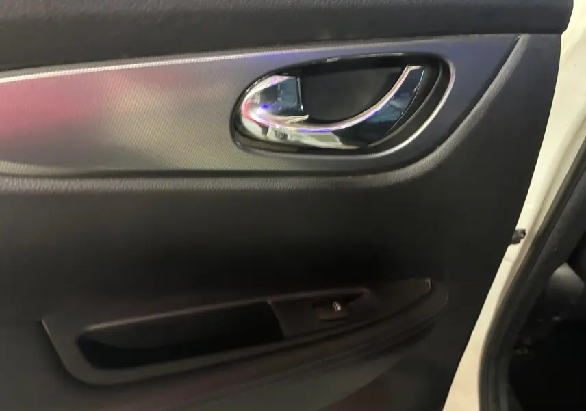Poignée de porte intérieure côté gauche du Nissan Qashqai blanc 2021, avec finition noire et insert chromé.