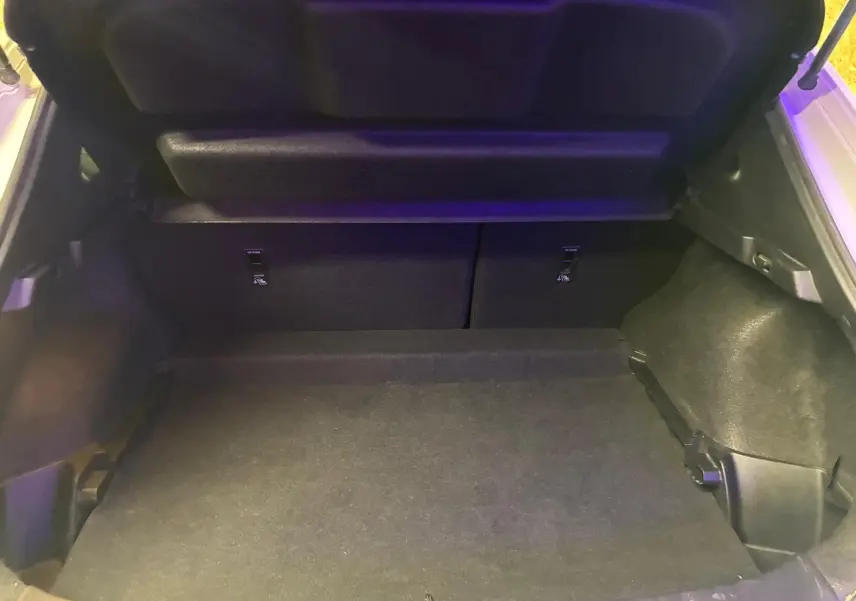 Coffre ouvert du Nissan Qashqai blanc 2021, vue intérieure montrant l'espace de chargement vide et le cache-bagages relevé.