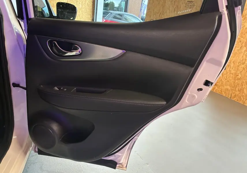 Vue intérieure de la porte arrière droite du Nissan Qashqai blanc 2021, avec garniture noire et poignée chromée.