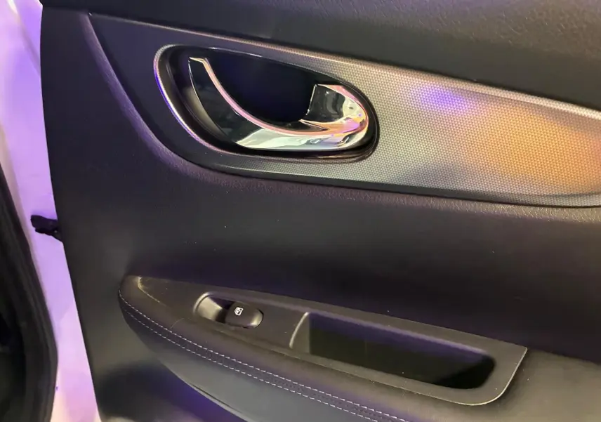 Gros plan sur la poignée intérieure chromée et le panneau de porte noir du Nissan Qashqai 1.5 BluedCi 2021 côté gauche.