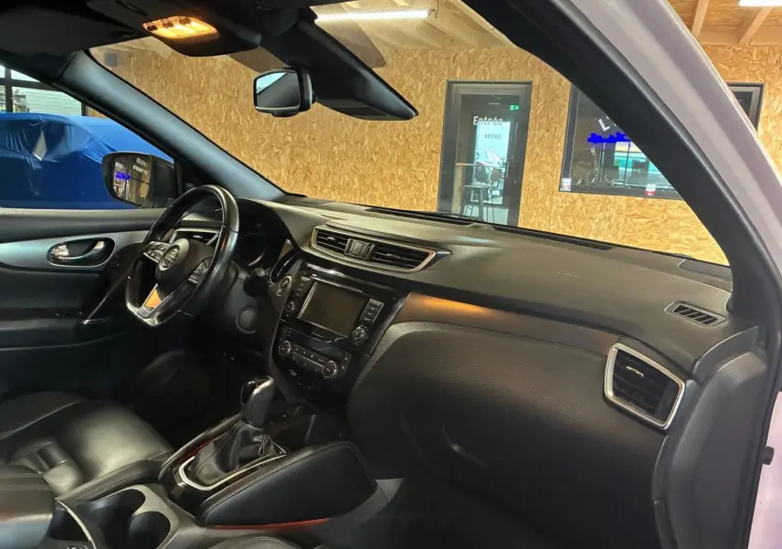 Vue intérieure côté conducteur du Nissan Qashqai blanc 2021, avec tableau de bord noir et sellerie cuir chauffante.