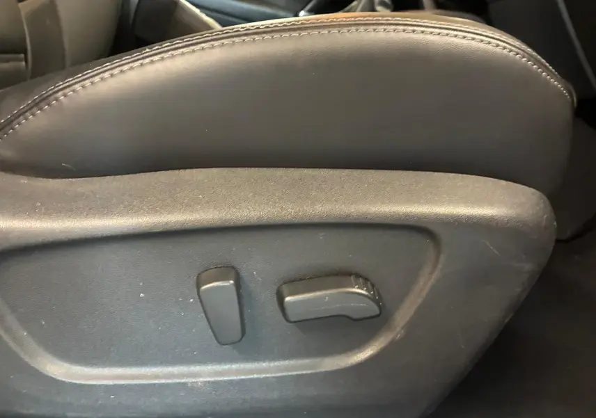 Détail des commandes électriques de réglage du siège avant en cuir noir du Nissan Qashqai blanc 2021.