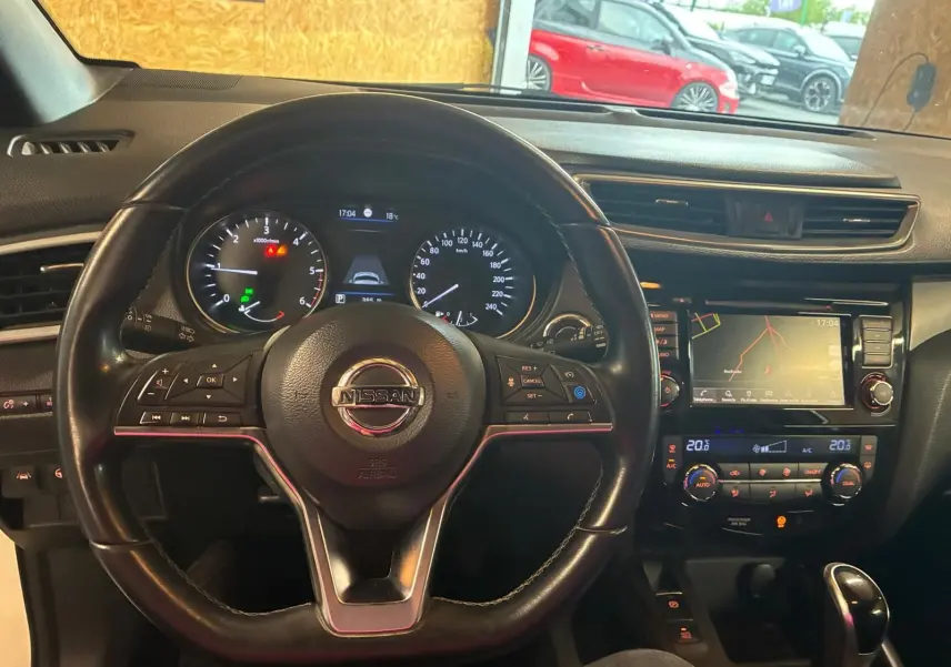 Vue intérieure centrée sur le volant cuir noir et le tableau de bord avec écran tactile du Nissan Qashqai blanc 2021.
