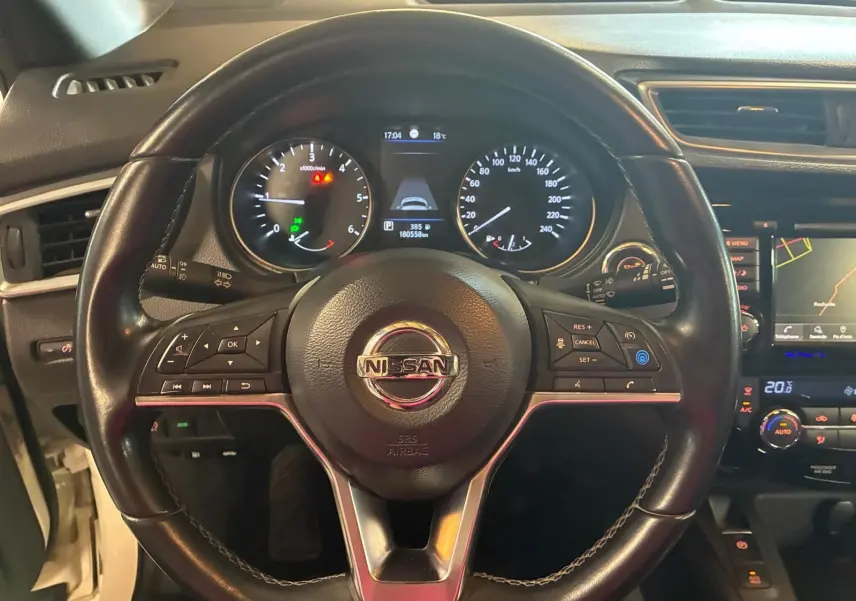 Vue rapprochée du volant en cuir noir du Nissan Qashqai 1.5 BlueDCI 115 Tekna+ avec tableau de bord et écran GPS visibles.