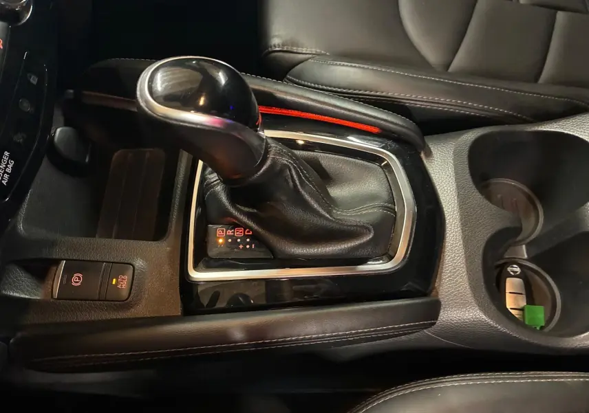 Gros plan sur la console centrale du Nissan Qashqai blanc 2021, mettant en valeur le levier de vitesse automatique et les commandes environnantes.