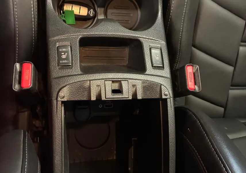 Vue plongeante sur la console centrale noire du Nissan Qashqai 1.5 BluedCi 115 Tekna+ avec porte-gobelets et sièges cuir chauffants.