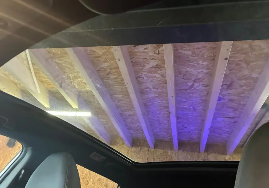 Toit panoramique ouvert vu de l'intérieur du Nissan Qashqai blanc 2021, avec sièges en cuir noir visibles.