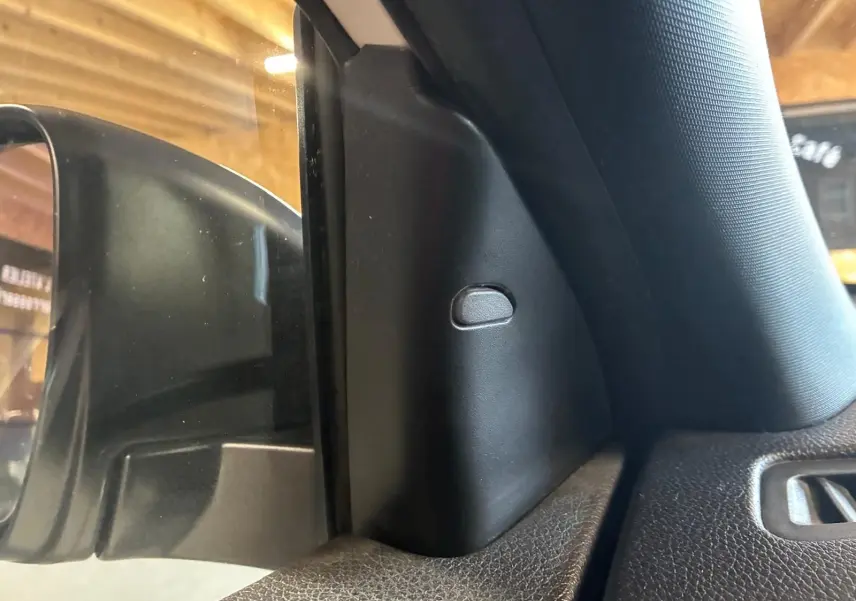 Détail intérieur montrant la garniture noire côté gauche près du rétroviseur d’un Nissan Qashqai blanc 2021.