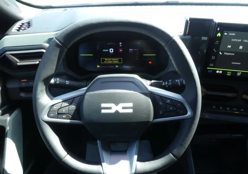 Vue rapprochée du volant noir du Dacia Duster 2025 hybride avec commandes intégrées et tableau de bord digital.