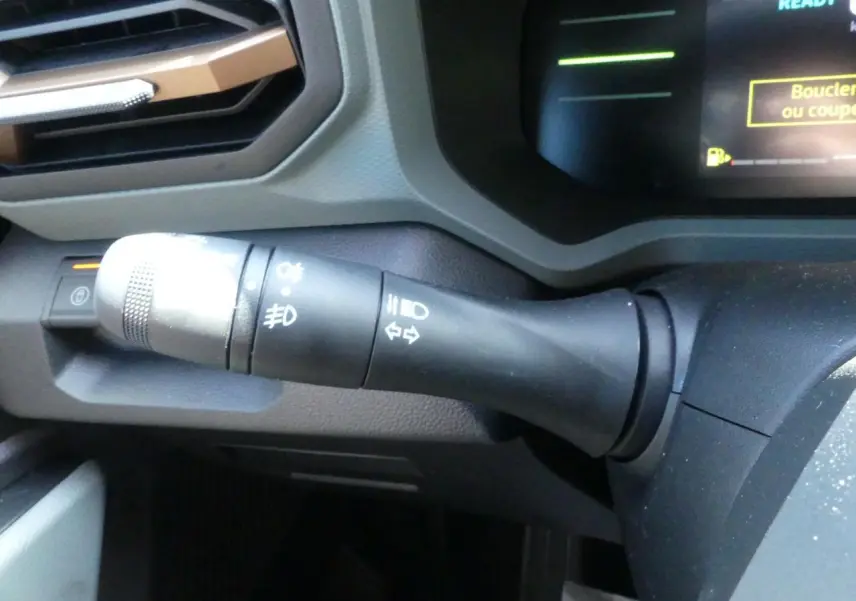 Gros plan sur la commande de clignotants et feux du tableau de bord du Dacia Duster blanc 2025.