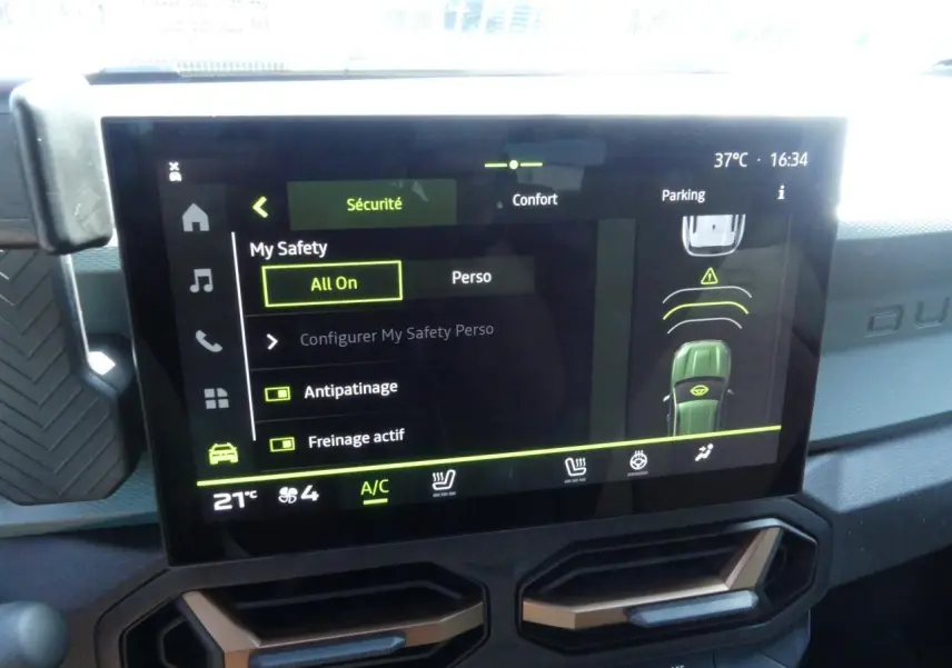 Écran tactile central du Dacia Duster 2025 affichant les options de sécurité et confort, avec détails en vert et noir.