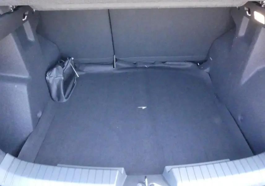 Coffre vide du Dacia Duster blanc 1.6 Hybrid 2025, vue intérieure arrière avec revêtement noir.