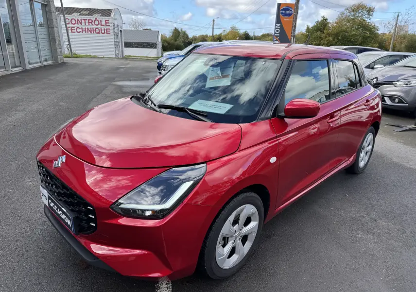Suzuki Swift 1.2 Hybrid Privilege 2025 en Burning Red Pearl, vue 3/4 avant droit avec calandre noire et jantes argentées.