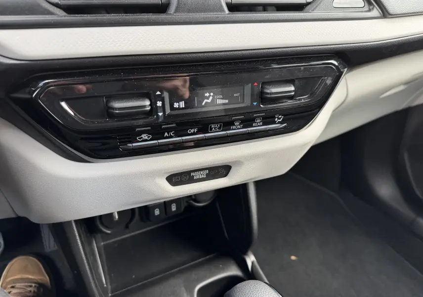 Vue rapprochée de la console centrale beige et noire de la Suzuki Swift 1.2 Hybrid Privilege avec commandes climatisation digitales.