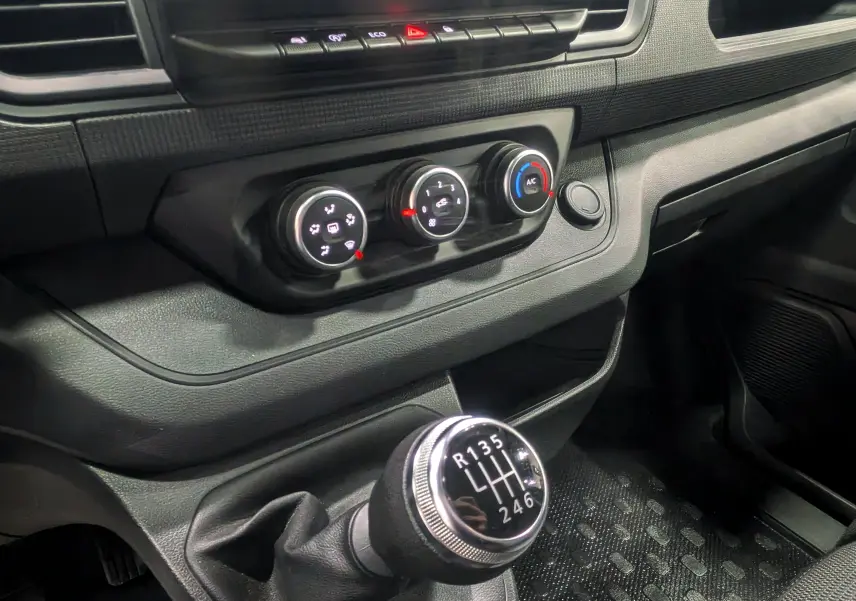 Gros plan sur la commande de boîte manuelle et les réglages de climatisation du Renault Trafic Combi gris Comète 2023.
