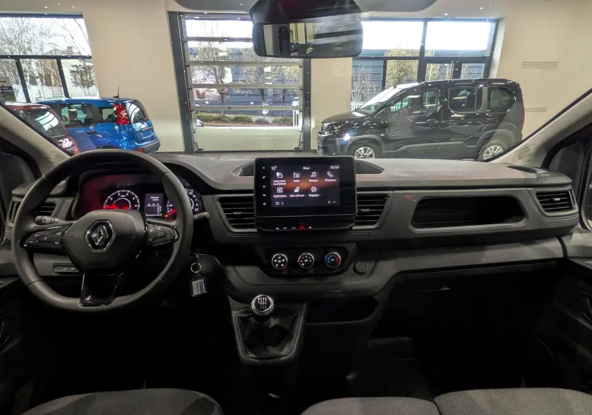 Vue intérieure du tableau de bord du Renault Trafic Combi gris, avec volant multifonction et écran tactile central.