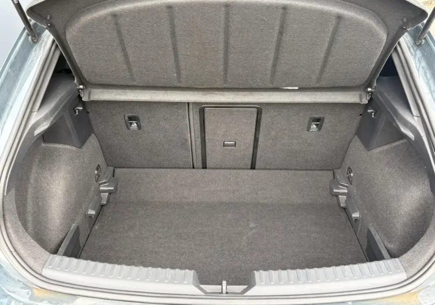 Coffre ouvert vu de l'arrière d'une CUPRA Leon 1.5 e-TSI 150 Bleu Fjord, intérieur de coffre en tissu gris.