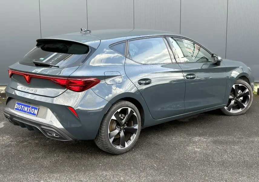 Vue 3/4 arrière droite d'une CUPRA Leon 2025 Bleu Fjord avec jantes alliage 18'' et bandeau lumineux arrière Tri-LED.