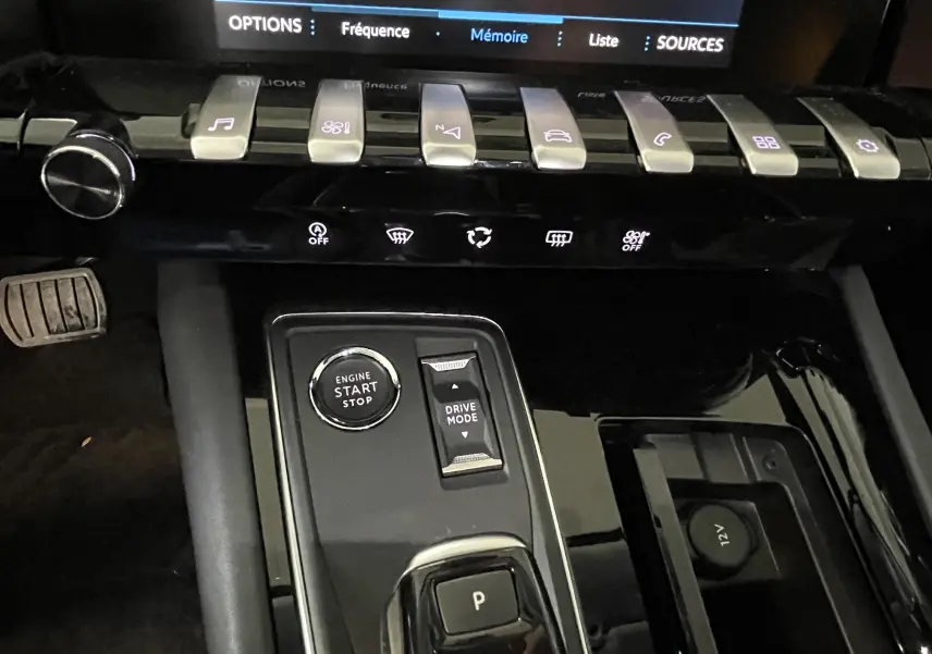 Gros plan sur la console centrale noire brillante du Peugeot 508 gris platinium, avec bouton start/stop et commandes de mode de conduite.