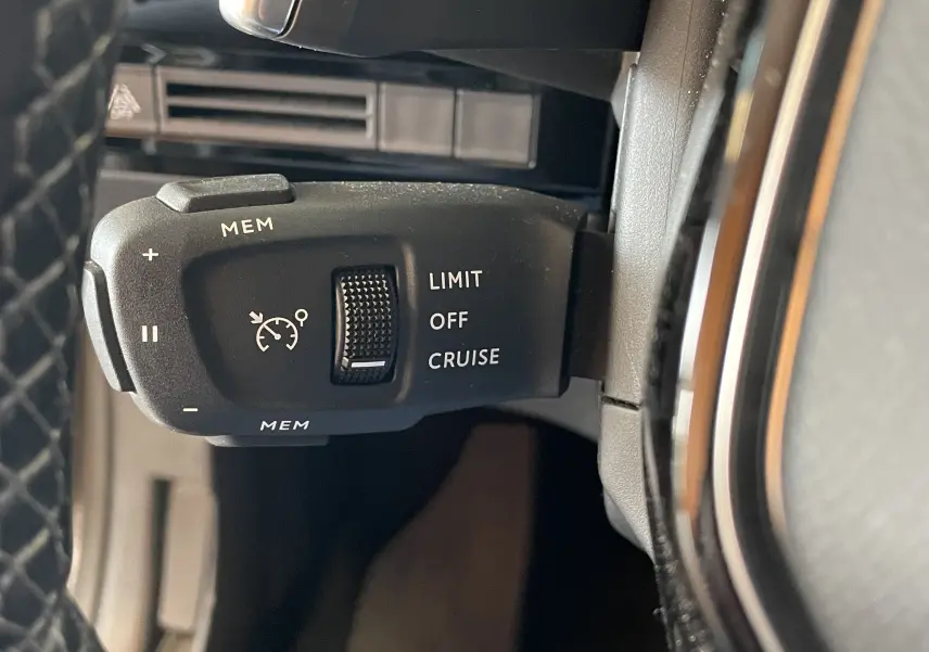 Gros plan sur la commande de régulateur de vitesse au volant d'une Peugeot 508 gris platinium de 2021.
