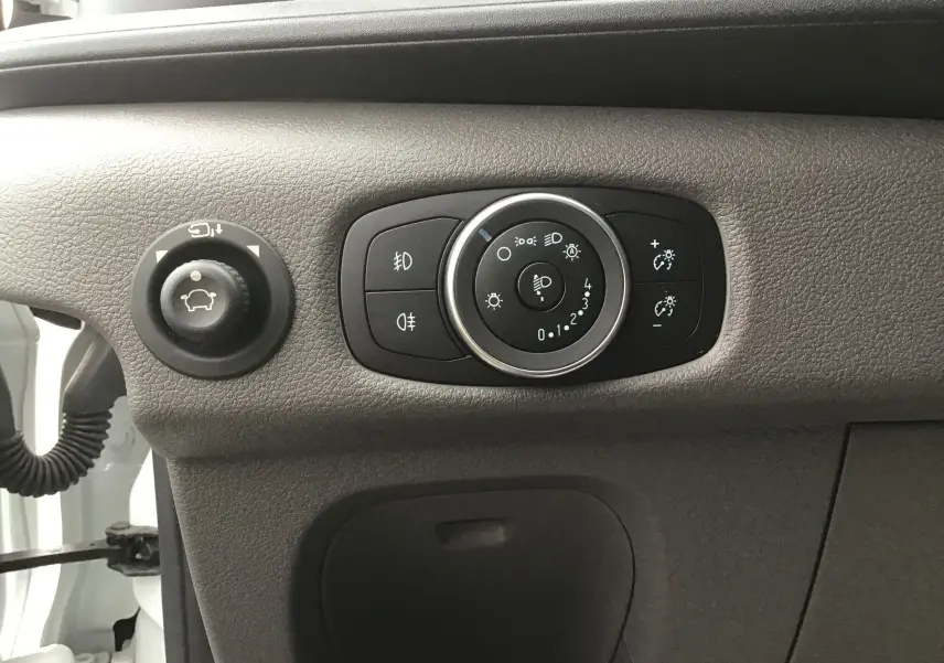 Gros plan sur les commandes d'éclairage et réglage des rétroviseurs du Ford Transit Chassis Cabine blanc, intérieur côté gauche.