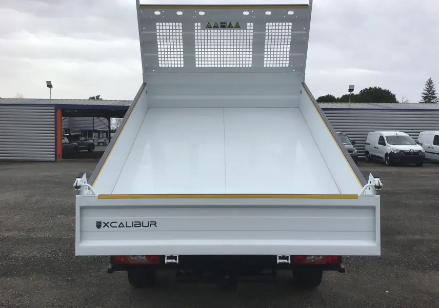 Vue arrière frontale d'un Ford Transit Chassis Cabine blanc avec benne relevée et coffre Xcalibur visible.