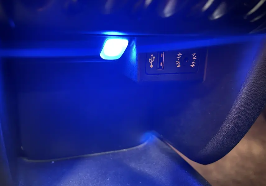 Prise USB et entrée AV-IN éclairées en bleu dans le coffre à gants d'une MINI Cabriolet rouge 2012.