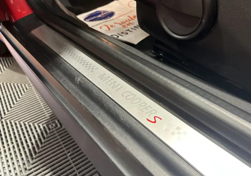 Vue intérieure de la MINI Cabriolet Cooper S rouge de 2012, avec tableau de bord et sièges en cuir rouge et noir.