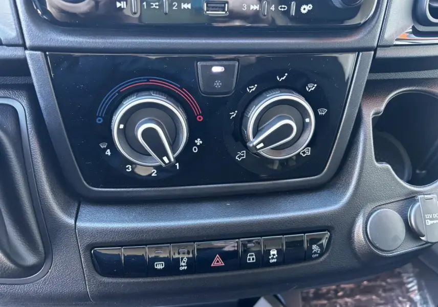 Gros plan sur les commandes de climatisation et les boutons de sécurité du tableau de bord du Peugeot Boxer Fourgon blanc.