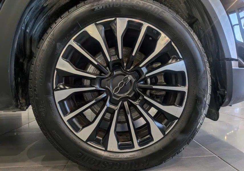 Gros plan sur la jante alliage bicolore noire et argentée du FIAT 500X noir Cinéma 2024 avec pneu Bridgestone.