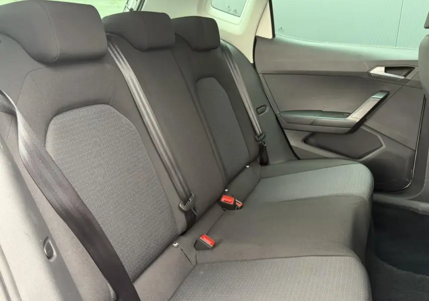 Vue intérieure du siège arrière droit de la SEAT Arona 2025, tissu gris foncé avec ceintures de sécurité visibles.