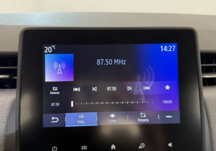 Écran tactile central de la Renault Clio noir affichant la radio FM à 87,50 MHz en intérieur jour