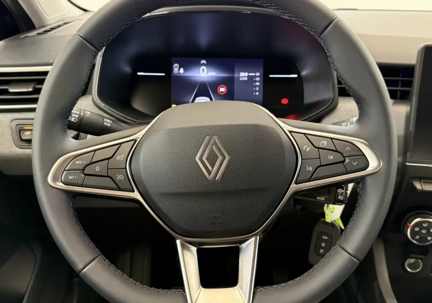 Vue rapprochée du volant cuir noir de la Renault Clio 2025 avec commandes multifonctions et tableau de bord numérique.