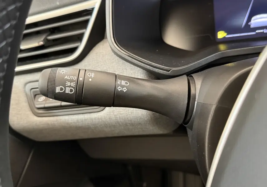 Gros plan sur la commande des phares et clignotants à gauche du volant dans l'habitacle d'une Renault Clio noire 2025.