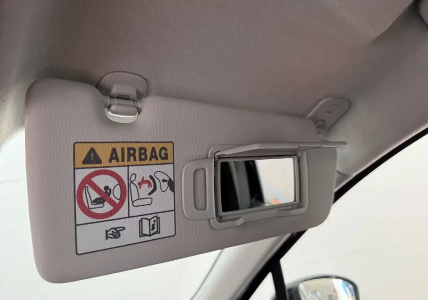 Détail du pare-soleil côté conducteur avec miroir ouvert et avertissement airbag dans une Renault Clio noire 2025.