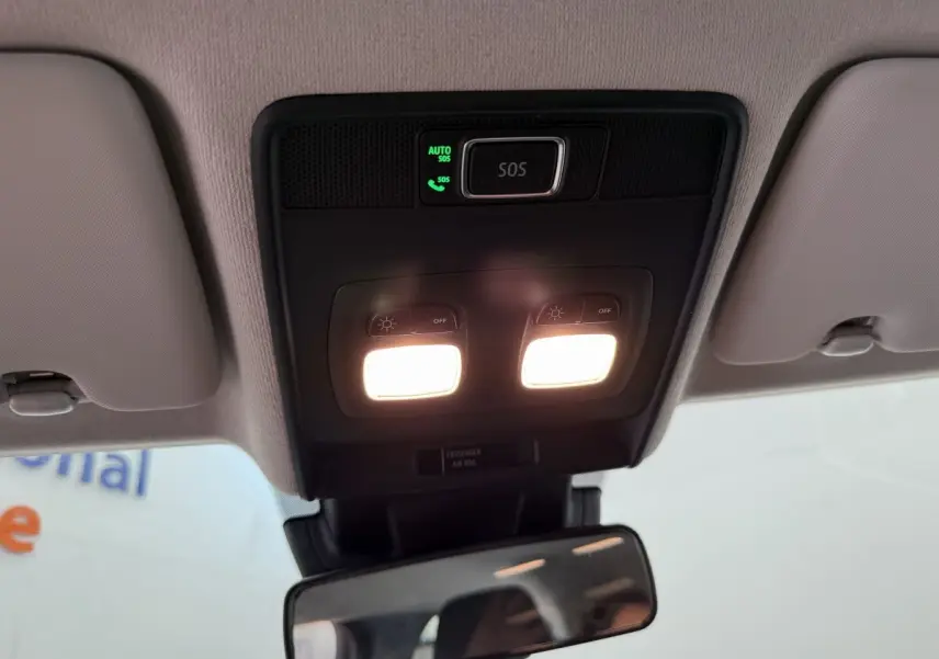 Plafonnier avec éclairage et bouton SOS dans l'habitacle clair d'une Renault Clio noire 2025 vue de l'intérieur avant.