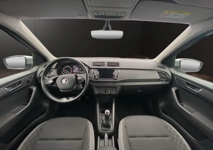 Vue intérieure frontale du tableau de bord et volant noir d'une Skoda Fabia gris argent, avec écran tactile et boîte manuelle.