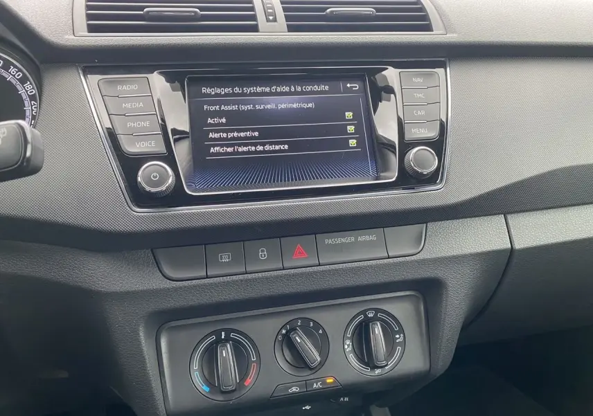 Vue rapprochée du tableau de bord gris argent d’une Skoda Fabia 2021, avec écran multifonction affichant les réglages d’aide à la conduite.