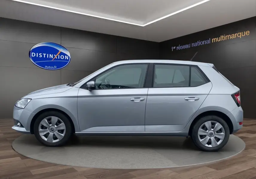 Vue de profil côté gauche d'une Skoda Fabia gris argent 2021 en finition Business, présentée en showroom.