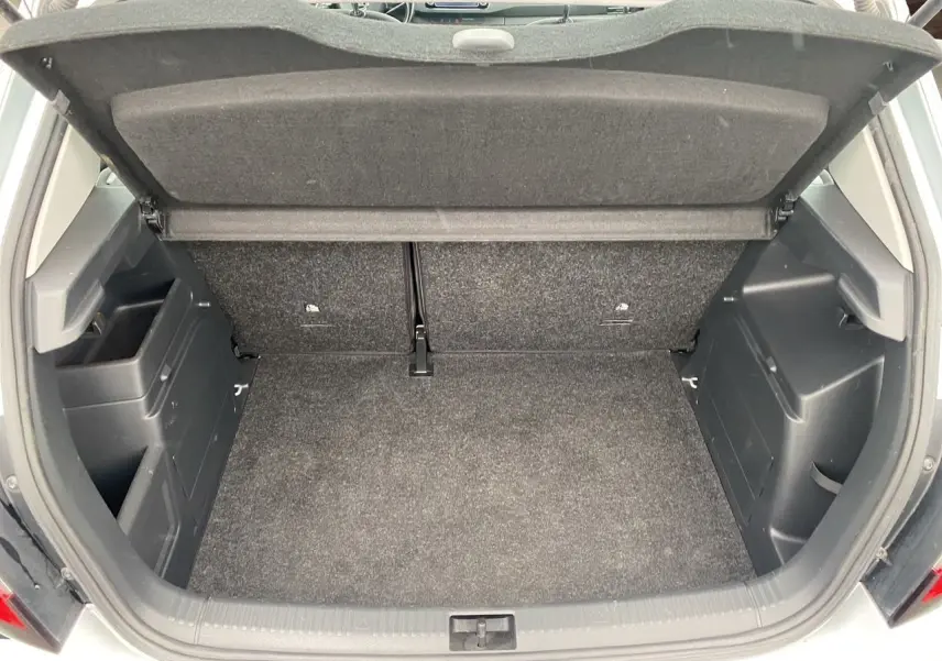 Coffre ouvert vu de l'arrière d'une Skoda Fabia gris argent, montrant l'espace de chargement et la tablette cache-bagages.