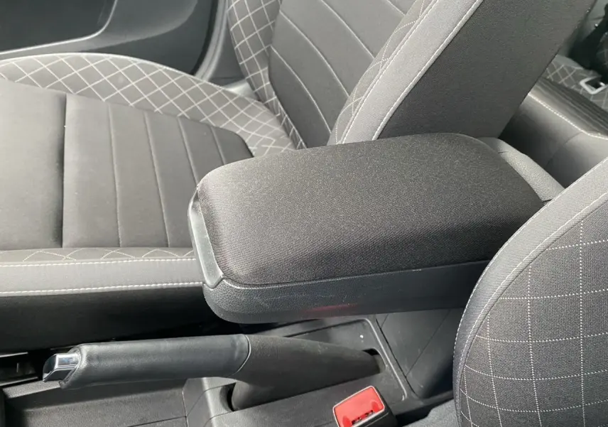 Gros plan sur l'accoudoir central et frein à main de la Skoda Fabia 2021, intérieur tissu gris à motifs croisés.