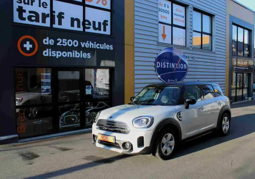 MINI Countryman gris perle métal avec toit noir, vue 3/4 avant droit devant un bâtiment commercial.