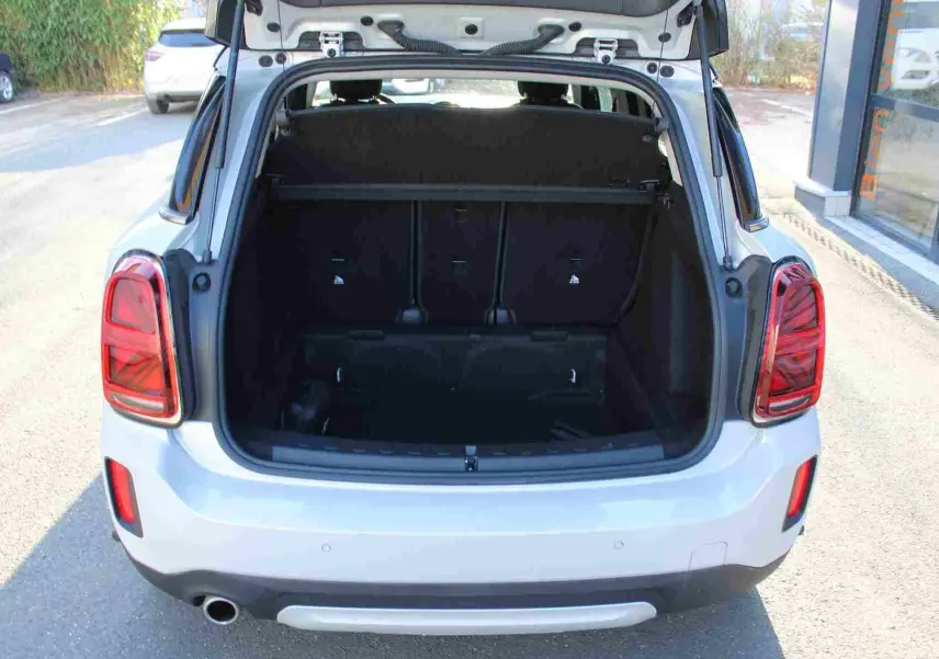 Vue arrière ouverte du coffre d'une MINI Countryman gris perle métal avec toit noir, montrant l'espace de chargement.