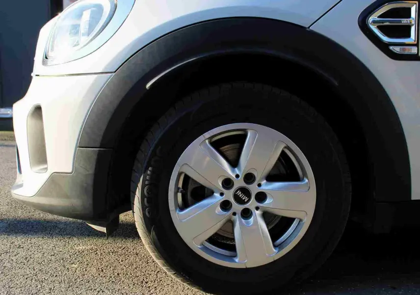 Gros plan sur la roue avant gauche d'une MINI Countryman gris perle métal avec jante alliage cinq branches.