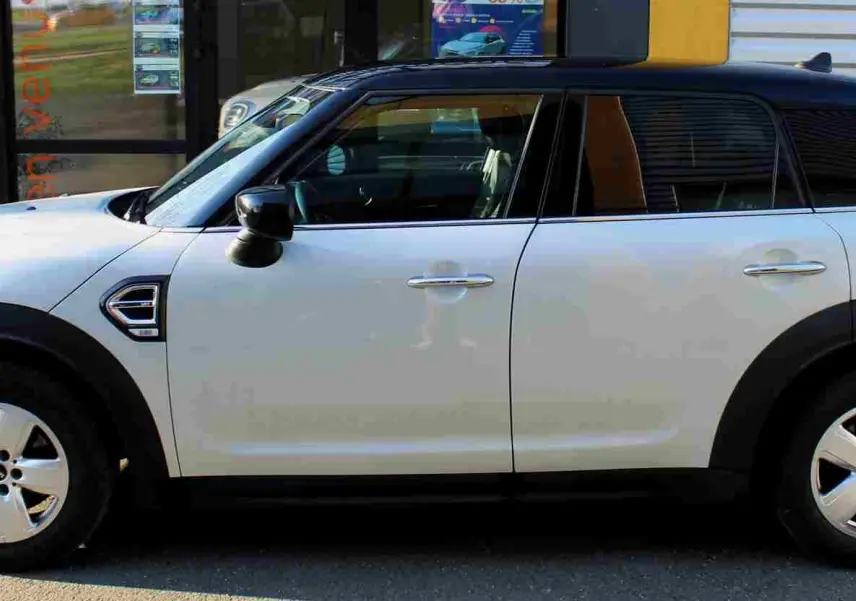 Vue de profil droit d'un MINI Countryman gris perle métallisé avec toit noir, jantes alliage et protections noires sur passages de roues.